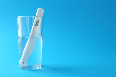 Photo of Nitrate tester in glass of water on light blue background, space for text