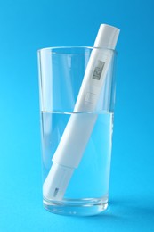 Photo of Nitrate tester in glass of water on light blue background, closeup