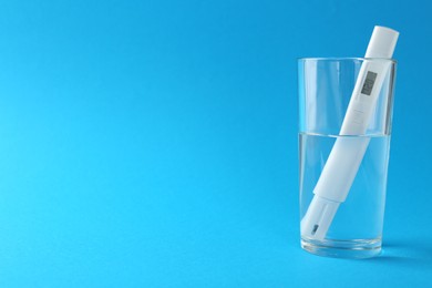 Photo of Nitrate tester in glass of water on light blue background, space for text