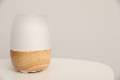 Photo of Modern aroma lamp on white table indoors. Space for text