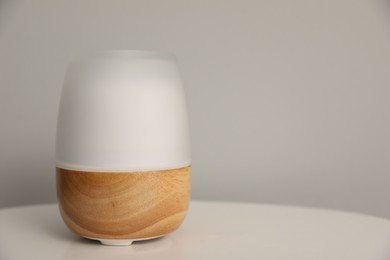 Photo of Modern aroma lamp on white table indoors. Space for text