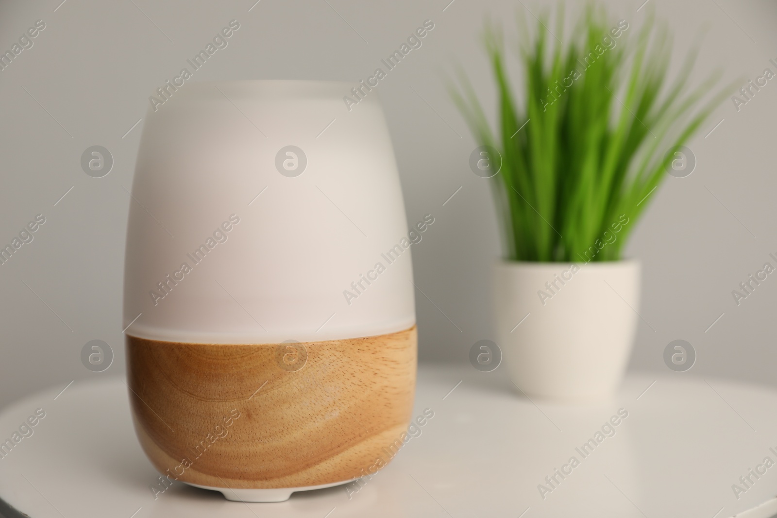 Modern aroma lamp and floral decor on white table indoors, closeup Photo of Modern aroma lamp and floral decor on white table indoors, closeup