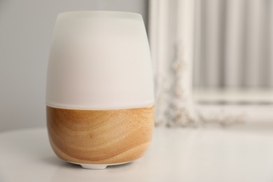 Photo of Modern aroma lamp on white table indoors, closeup. Space for text
