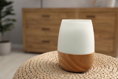 Photo of Modern aroma lamp on wicker surface indoors. Space for text
