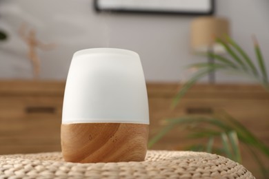 Photo of Modern aroma lamp on wicker surface indoors