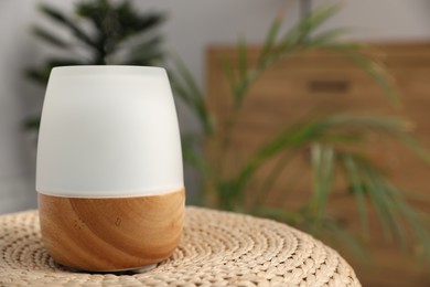 Photo of Modern aroma lamp on wicker surface indoors. Space for text