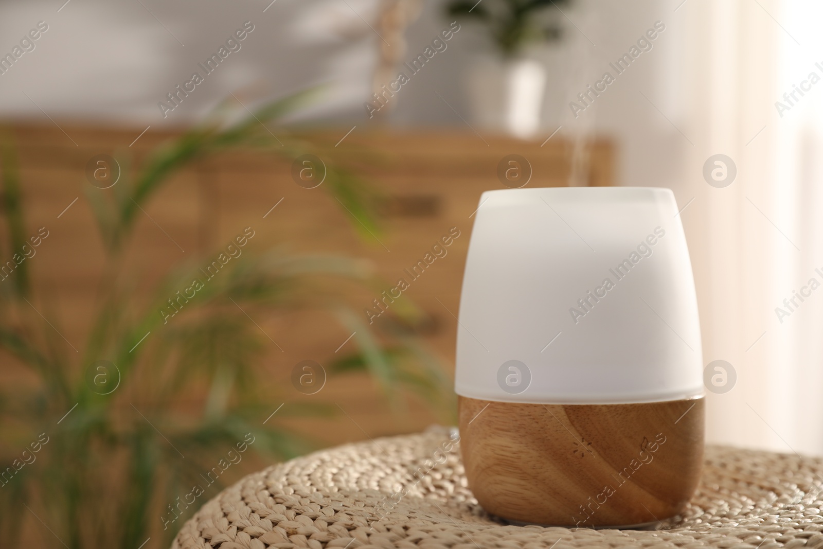Modern aroma lamp on wicker surface indoors. Space for text Photo of Modern aroma lamp on wicker surface indoors. Space for text
