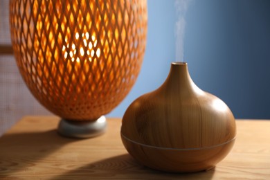 Photo of Modern aroma lamp on wooden table indoors, closeup