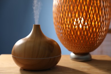Photo of Modern aroma lamp on wooden table indoors, closeup