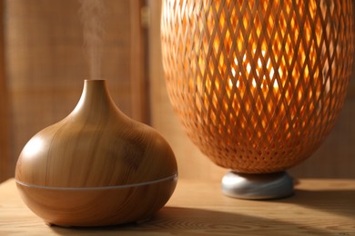 Photo of Modern aroma lamp on wooden table indoors, closeup
