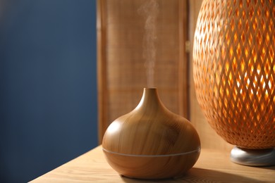 Photo of Modern aroma lamp on wooden table indoors