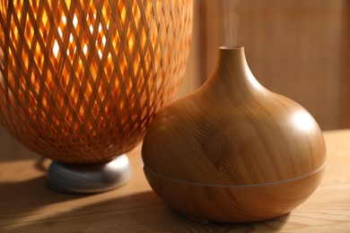 Photo of Modern aroma lamp on wooden table indoors, closeup