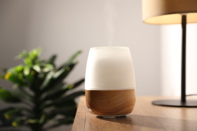 Photo of Modern aroma lamp on wooden table indoors