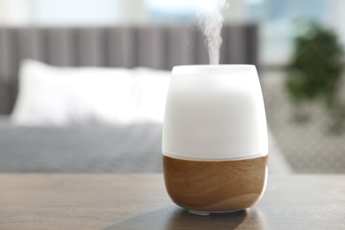Photo of Modern aroma lamp on wooden table indoors. Space for text