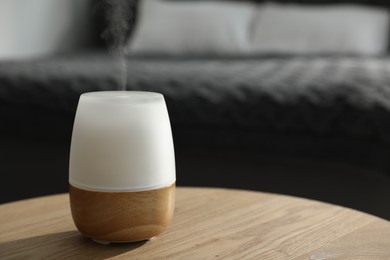 Photo of Modern aroma lamp on wooden table indoors. Space for text
