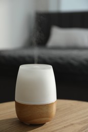 Photo of Modern aroma lamp on wooden table indoors, closeup