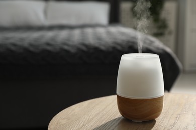 Photo of Modern aroma lamp on wooden table indoors. Space for text