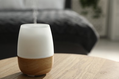 Photo of Modern aroma lamp on wooden table indoors, closeup. Space for text
