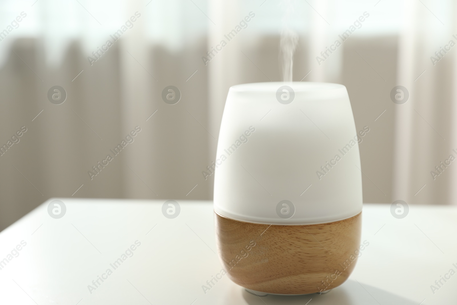 Modern aroma lamp on light table indoors, closeup. Space for text Photo of Modern aroma lamp on light table indoors, closeup. Space for text
