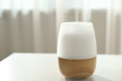 Photo of Modern aroma lamp on light table indoors, closeup. Space for text