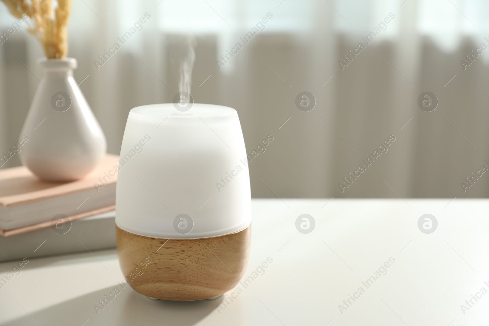 Modern aroma lamp on light table indoors. Space for text Photo of Modern aroma lamp on light table indoors. Space for text