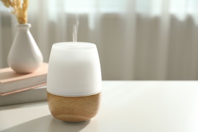 Photo of Modern aroma lamp on light table indoors. Space for text