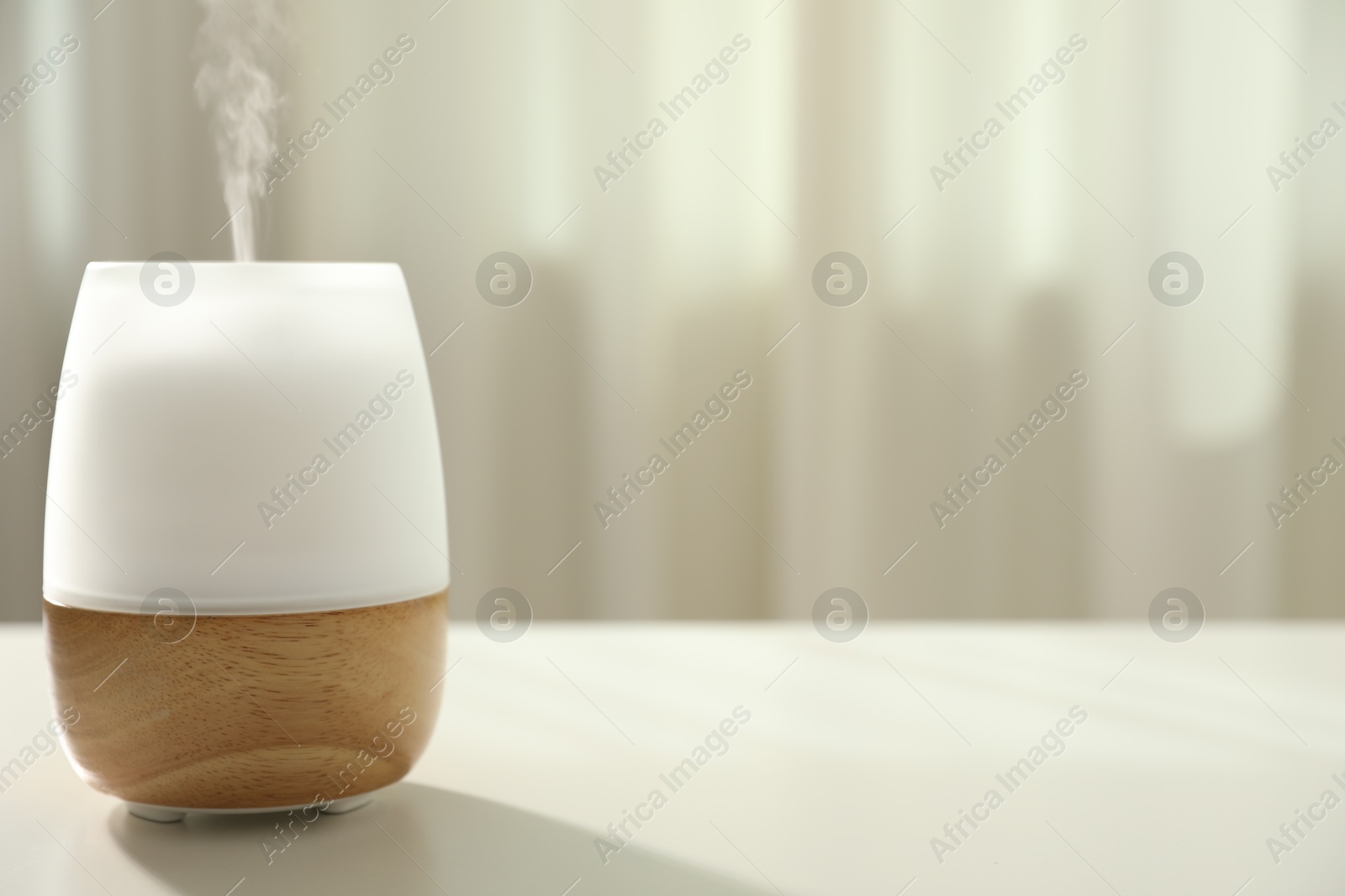 Modern aroma lamp on light table indoors. Space for text Photo of Modern aroma lamp on light table indoors. Space for text