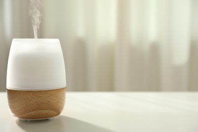 Photo of Modern aroma lamp on light table indoors. Space for text