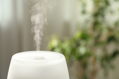 Photo of Modern aroma lamp against blurred background, closeup. Space for text