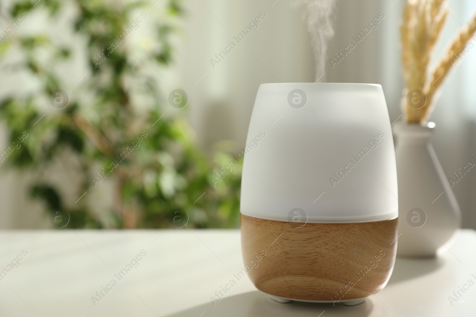 Modern aroma lamp on light table indoors. Space for text Photo of Modern aroma lamp on light table indoors. Space for text