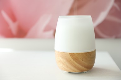 Photo of Modern aroma lamp on white wooden table, closeup. Space for text