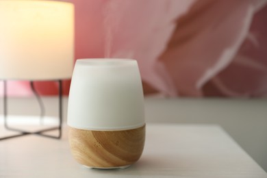Photo of Modern aroma lamp on white wooden table, closeup