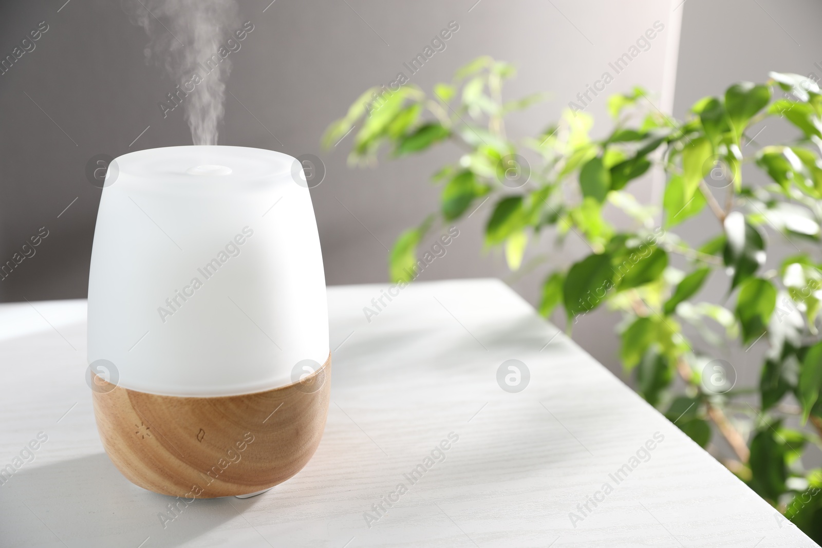 Modern aroma lamp on white wooden table indoors Photo of Modern aroma lamp on white wooden table indoors