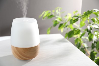 Photo of Modern aroma lamp on white wooden table indoors