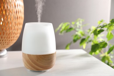 Photo of Modern aroma lamp on white wooden table indoors