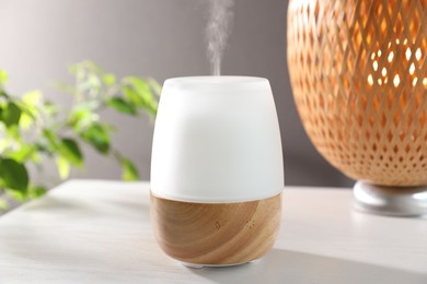 Photo of Modern aroma lamp on white wooden table indoors