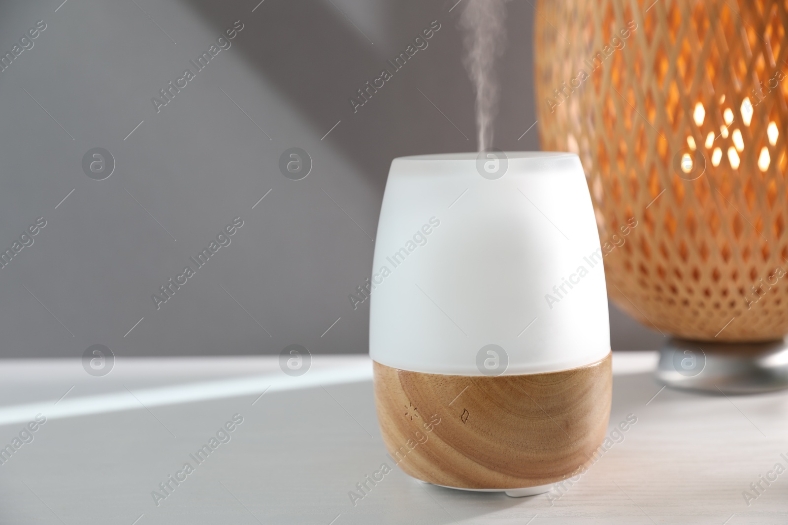 Modern aroma lamp on white wooden table indoors. Space for text Photo of Modern aroma lamp on white wooden table indoors. Space for text