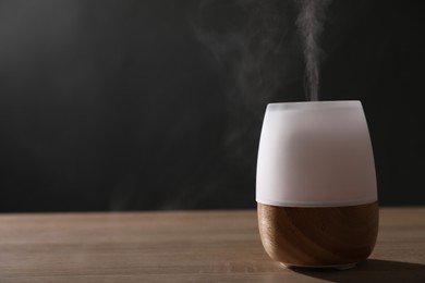 Photo of Modern aroma lamp on wooden table indoors. Space for text