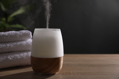 Photo of Modern aroma lamp on wooden table indoors. Space for text