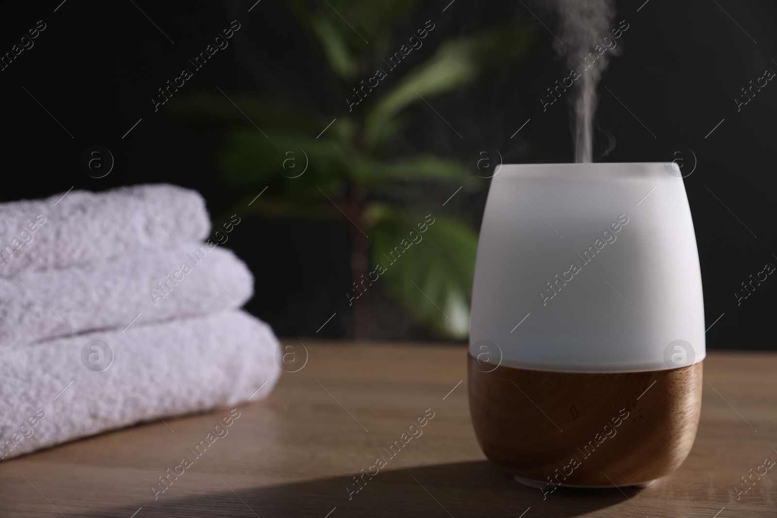 Modern aroma lamp on wooden table indoors Photo of Modern aroma lamp on wooden table indoors