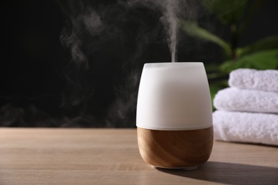 Photo of Modern aroma lamp on wooden table indoors. Space for text