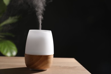 Photo of Modern aroma lamp on wooden table indoors. Space for text