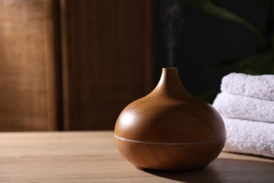 Photo of Modern aroma lamp on wooden table indoors, closeup. Space for text