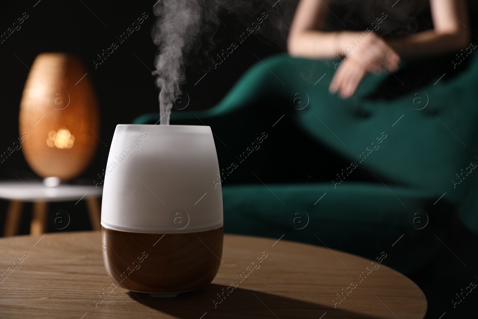 Woman near armchair indoors, focus on modern aroma lamp Photo of Woman near armchair indoors, focus on modern aroma lamp