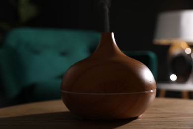 Photo of Modern aroma lamp on wooden table indoors, closeup