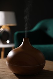 Photo of Modern aroma lamp on wooden table indoors, closeup