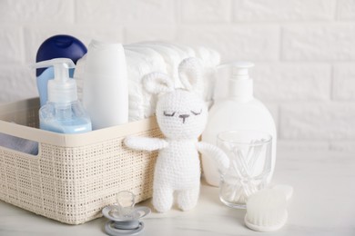 Photo of Many different baby accessories and toy bunny on table near brick wall