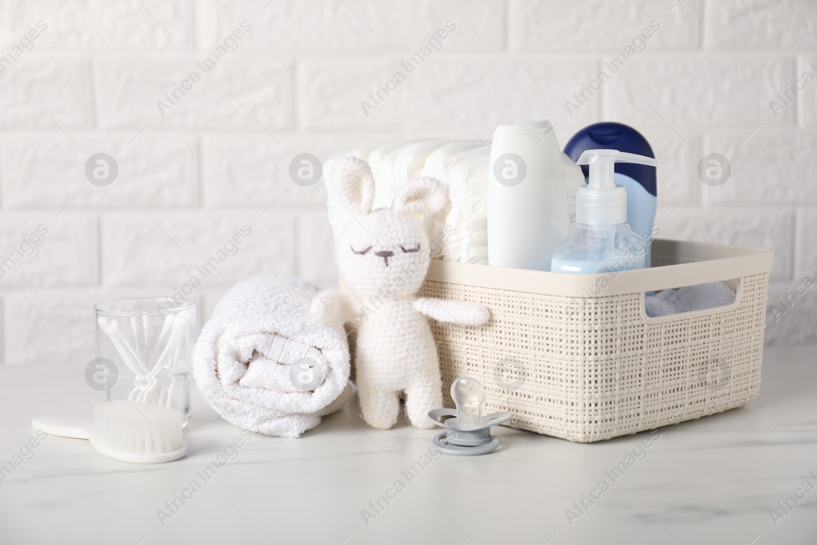 Photo of Many different baby accessories and toy bunny on table near brick wall