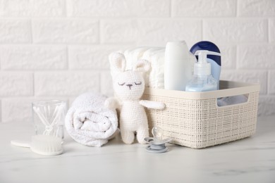 Photo of Many different baby accessories and toy bunny on table near brick wall