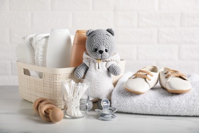 Photo of Many different baby accessories and toy bear on table near brick wall